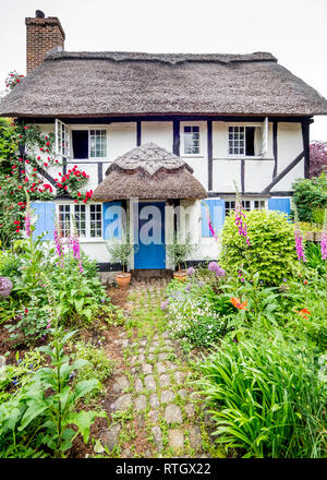 Eine fundamentale Chocolate Box Postkarte typischen reetgedeckten alten Tudor Jacobean Englisch Ferienhaus mit Garten in voller Blüte Stockfoto