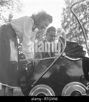 Eltern in den 1950er Jahren. Eine stolze Mutter und Vater sind mit Blick auf ihr Kind im Kinderwagen. Der Kinderwagen hat ein typisches 40er Jahre Design mit einem hölzernen Körper in schwarz lackiert. Beachten Sie die Chrom Details auf der Seite, die die Räder. Foto Kristoffersson ref AX 39-7 Schweden 1950 Stockfoto