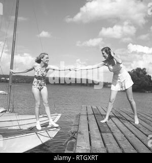 1940 Sommer. Zwei junge an einem Jachthafen an einem Sommertag. Die Mädchen erhalten vom Boot aus auf die Brücke braucht eine helfende Hand. Foto Kristoffersson ref P 13-5. Schweden 1945 Stockfoto
