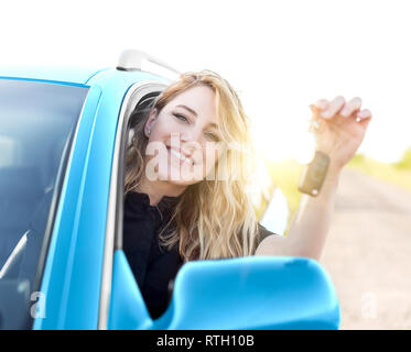 Junge attraktive Frau sucht werden die Tasten angezeigt, die von dem neuen Auto. Stockfoto