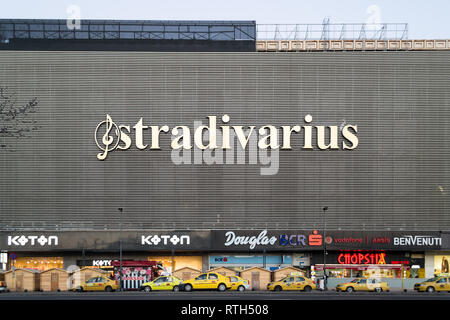 Bukarest, Rumänien - 17. Februar 2019: Unirea Shopping Center Gebäude mit gelben Taxis vor geparkt und Logos wie Stradivari, Koton, Dougl Stockfoto