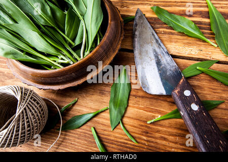 Bündel von frischem Bärlauch mit einem alten Messer auf Holz- strukturierten Hintergrund. Stockfoto