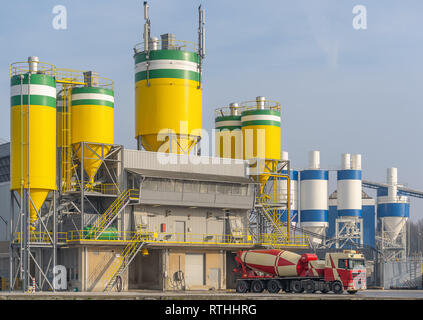 Konkrete Fahrzeug wartet im Betonwerk, bis es mit frischen Beton gefüllt ist. Klar die Silos der Fabrik zu sehen, in denen der Ra werden Stockfoto