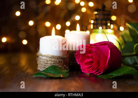 Rote Rose und Laterne mit Lichtern, Kerzen auf einem Holztisch. Romantische Konzept Stockfoto