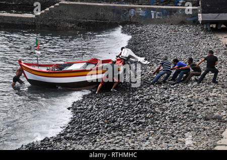 Um Madeira - Fischer am Ende eines langen Tages, ihr Boot ziehen bis auf einen Kiesstrand in Camara de Lobos. Stockfoto