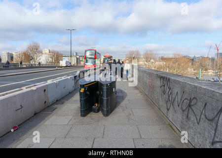 Anti-Fahrzeug Poller, einer Anti-terror-Sicherheit messen, auf dem Gehsteig der Waterloo Bridge, Lambeth, London SE1, red London Bus Stockfoto