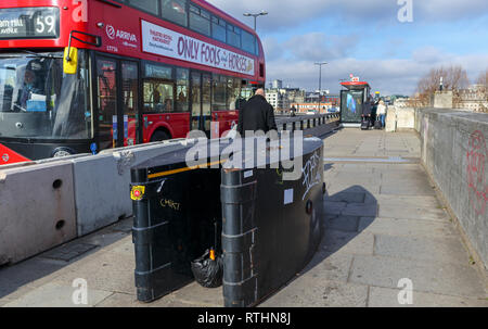 Anti-Fahrzeug Poller, einer Anti-terror-Sicherheit messen, auf dem Gehsteig der Waterloo Bridge, Lambeth, London SE1, red London Bus Stockfoto