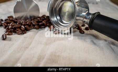 Kaffeebohnen auf Leinen mit stamper und Filterhalter kurz vor der Zubereitung. Stockfoto