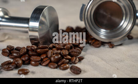 Kaffeebohnen auf Leinen mit stamper und Filterhalter kurz vor der Zubereitung. Stockfoto