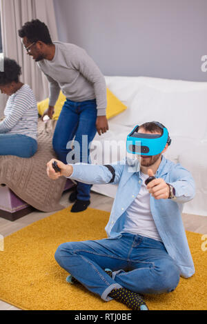 Gruppe von multucultural Freunden Spaß zu Hause spielen 3D-Spiel mit Hi-tech vitrual Realität Viewer für Spiele. Fokus auf kaukasischer Mann in Blau Virt Stockfoto