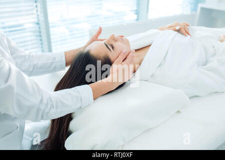 Gesichtsbehandlung Wellness Kosmetik Prozedur, Ansicht von oben. Skin Care lift Anti age Massage. Kaukasische brünette Frau in Weiß Bademantel bekleidet, anti-wrinkl Stockfoto