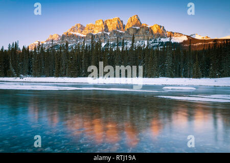 Sonnenuntergang lange Belichtung der späten Sonne Verfangen oben auf der schneebedeckten Castle Mountain und das Bow River im Banff National Park, Kanada Stockfoto