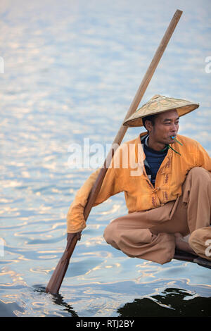 Porträt eines burmesischen Fischers, der auf einem Holzboot in Inle Lake, Myanmar, Tabak raucht. Stockfoto