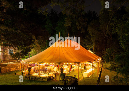 Eine Hochzeit Zelt in der Nacht von Bäumen mit einem orangefarbenen Leuchten von den Lichtern umgeben, Langzeitbelichtung - Hochzeit Zelt Serie Stockfoto