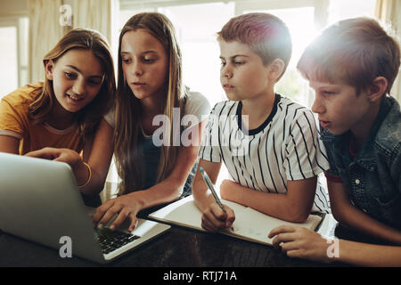 Gruppe von Kindern zusammen lernen auf einem Laptop. Junge Mädchen Unterricht Unterricht an ihre Geschwister zu Hause auf dem Laptop. Stockfoto