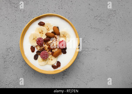 Müsli, Joghurt, Obst und Nüsse in der Schale am Tisch serviert Stockfoto