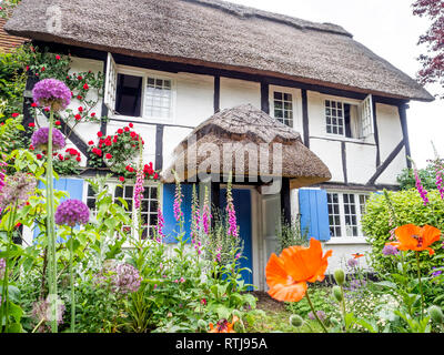 Eine fundamentale Chocolate Box Postkarte typischen reetgedeckten alten Tudor Jacobean Englisch Ferienhaus mit Garten in voller Blüte Stockfoto