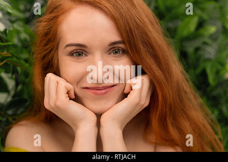 Neugierig rothaarige Frau pillowing Gesicht in ihren Händen Stockfoto