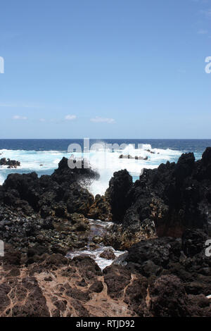 Wellen, die in Lava Rock am Ufer des Laupahoehoe Point auf der Hamakua Coast, Hawaii, USA Stockfoto