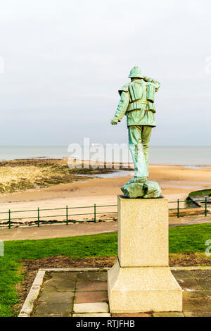 Bronzestatue des Rettungsbootes Mann an Nayland Rock, mit Blick hinter die Sands, Gezeiten rock Regal und dann das Meer mit Schiff am Horizont. Engen Fokus. Stockfoto