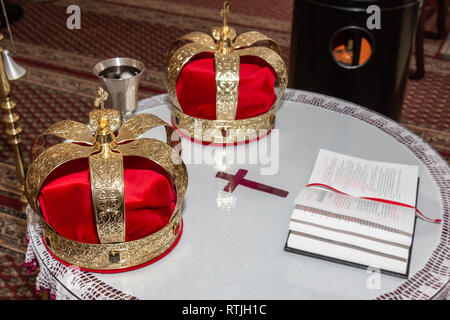 Hochzeit goldene Kronen, alten Kelch mit Wein und offene Bibel für Hochzeit in der serbisch-orthodoxen Kirche bereit. Stockfoto