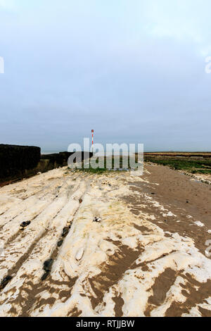 Konkrete Wave Breaker mit Navigation Pol am Ende, ragt heraus auf die Gezeiten Regal von Kreide und Sand, der am Ufer des Meeres, Margate. Düster bedeckt grauer Himmel. Stockfoto