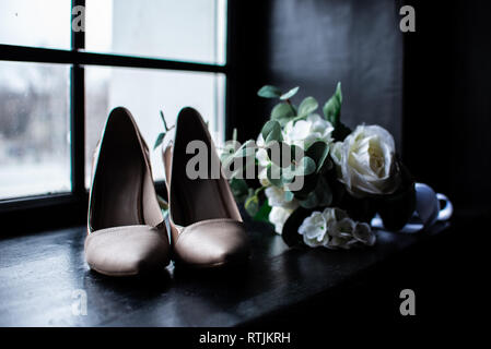 White Wedding Bouquet und rosa Schuhe der Braut in der Nähe der Fenster. Stockfoto