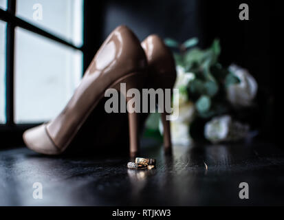 Hochzeit Schuhe und Brautstrauß, Hochzeit goldene Ringe. Stockfoto