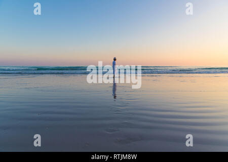 Traditioneller omanischer Mann, der an einem Strand in Mughsail Beach, Salalah, Oman spaziert Stockfoto