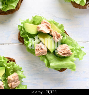 In der Nähe von Thun Sandwiches mit Avocado und Salatblätter. Lecker Thunfisch Brötchen zum Frühstück. Gesunden Snack. Ansicht von oben, flach Stockfoto