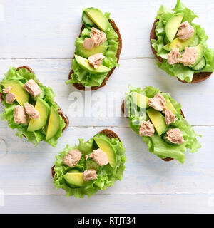 Thunfisch Sandwiches mit Avocado und Salatblätter über hellen Hintergrund. Lecker Thunfisch Brötchen zum Frühstück. Gesunden Snack. Ansicht von oben, flach Stockfoto