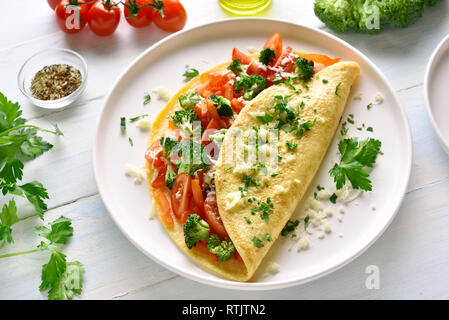 Omelett mit Tomaten, rote Paprika und Brokkoli auf hellem Holztisch. Gesunde Ernährung Essen zum Frühstück. Lecker morgen essen. Stockfoto