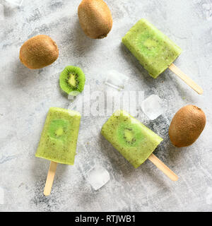 Obst Eis am Stiel von Kiwi über Stein Hintergrund. Ansicht von oben, flach Stockfoto
