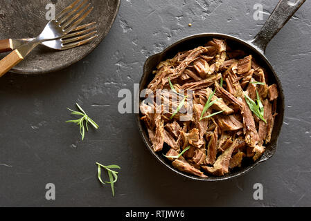 Zog Rindfleisch für Sandwiches in der Pfanne auf dem schwarzen Stein. Ansicht von oben Stockfoto