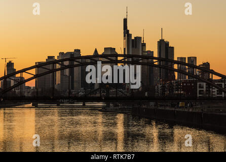 27. Februar 2019, Hessen, Frankfurt/Main: Die Frankfurter Skyline und den Main hinter die Deutschherrnbrücke in der untergehenden Sonne. Foto: Frank Rumpenhorst/dpa Stockfoto