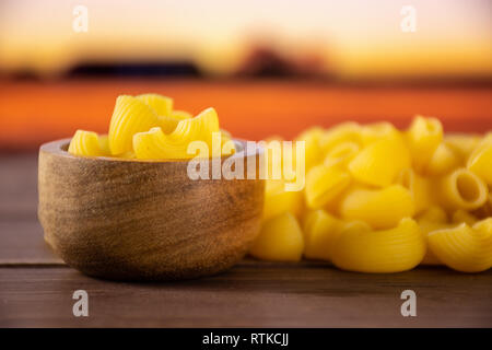 Menge ganze rohe Nudeln Pipe Rigate Sorte mit Holzschale mit Herbst Feld Stockfoto