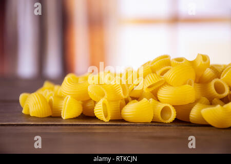 Menge ganze rohe Nudeln Pipe Rigate Sorte Stack mit seidenen Vorhängen hinter Stockfoto