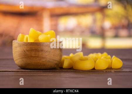 Menge ganze rohe Nudeln Pipe Rigate Vielzahl Heap mit Holzschale mit Warenkorb Stockfoto