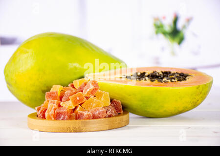 Gruppe von einer ganzen Hälfte viele Schichten von trockenen Papaya auf Bambus Platte mit roten Blumen auf Weiß Stockfoto