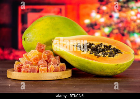 Gruppe von einer ganzen Hälfte viele Schichten von trockenen Papaya auf Bambus Platte mit Weihnachtsbaum in Rot Stockfoto