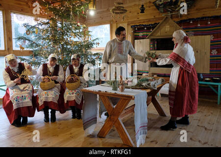 Belarussische Dorfbewohner in traditionellem Gewand, die eine Krippenkrippe für die Geburt Jesu während der Weihnachtsfeier im Dorf Stoily im Bezirk Pruschany der Region Brest in Weißrussland einrichten Stockfoto