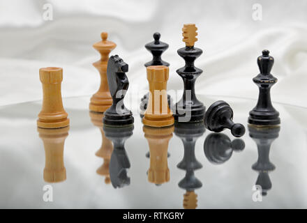 Schwarz und leichte Schachfiguren auf einem Spiegel mit glänzenden weißen Hintergrund Stockfoto