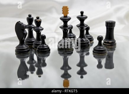 Schwarze Schachfiguren auf einem Spiegel mit glänzenden weißen Hintergrund Stockfoto