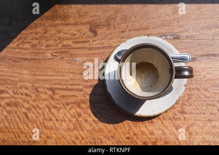 Blick von oben auf die leeren Kaffee Keramik Schale auf hölzernen Schreibtisch mit morgen Licht Stockfoto