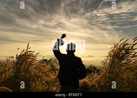 Silhouette Mann glücklich mit Hände erheben sich auf dem Berg mit sunrise Himmel. Man Fernweh Natur ständigen offenen Armen genießen Sonne Konzept Stockfoto