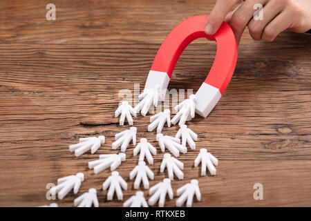 Nahaufnahme von einer Person die Hand halten Roten Hufeisen Magnet für Weiße menschliche Figur Stockfoto