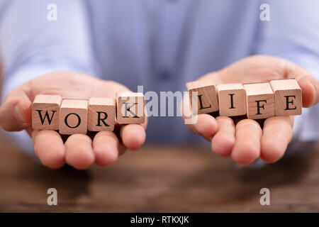 Nahaufnahme der Geschäftsmann Hand Balancing Arbeit und Leben Bausteine über Holz- Tabelle Stockfoto