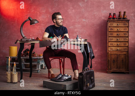 Junge kreative Schuster erfinden schicke Schuhe, volle Länge Foto Stockfoto