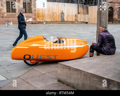 Straßburg, Frankreich - Okt 1, 2017: velomobiel Quest orange Velomobil Fahrzeug mit Fahrer warten in der Nähe des abgestellten Fahrzeugs in das Zentrum von Straßburg Stockfoto