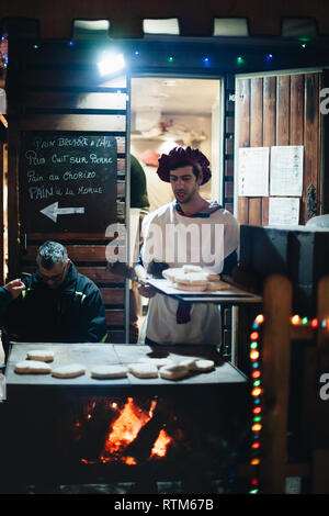 Straßburg, Frankreich - Dec 23, 2017: Junger Mann, die traditionelle portugiesische Brot Typen mit Chorizo Wurst und andere Zutaten auf dem Weihnachtsmarkt in Straßburg, Frankreich Stockfoto